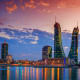 Bahrain skyline at sunset with illuminated modern skyscrapers reflected in calm water